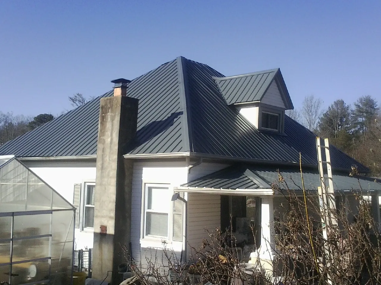 Dark blue standing seam metal roof on a white farmhouse with dormer — Slate & Tile Roof Repair by Roofing Brothers in Chickamauga