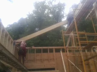Carpenter raising a rafter beam on a new second story frame in Chickamauga