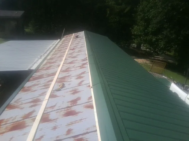 Old rusted panels beside newly installed green metal roofing — Wind Damage Roof Repair by Roofing Brothers in Chickamauga