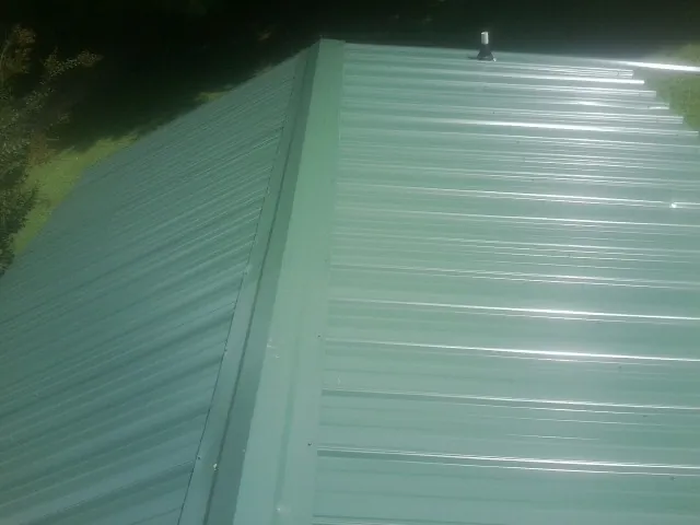 New green metal panels meeting at the ridge of a roof — Flat Roof Repair work by our crew in Chickamauga