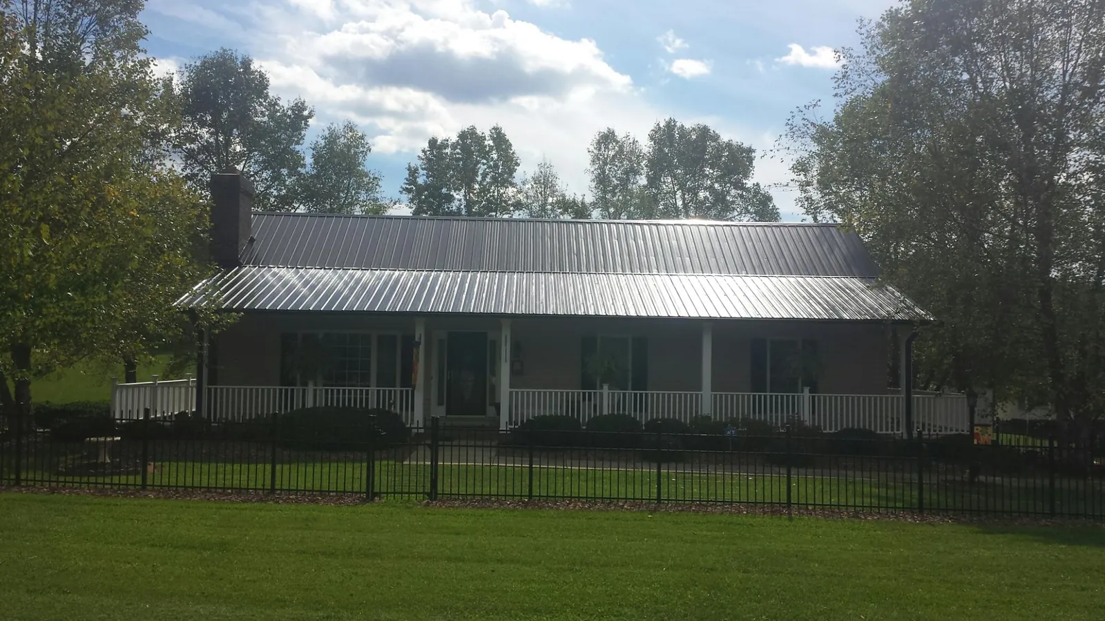 Gray metal roof on a brick ranch with a full width front porch — Gutter Guard Installation work by our crew in Chickamauga
