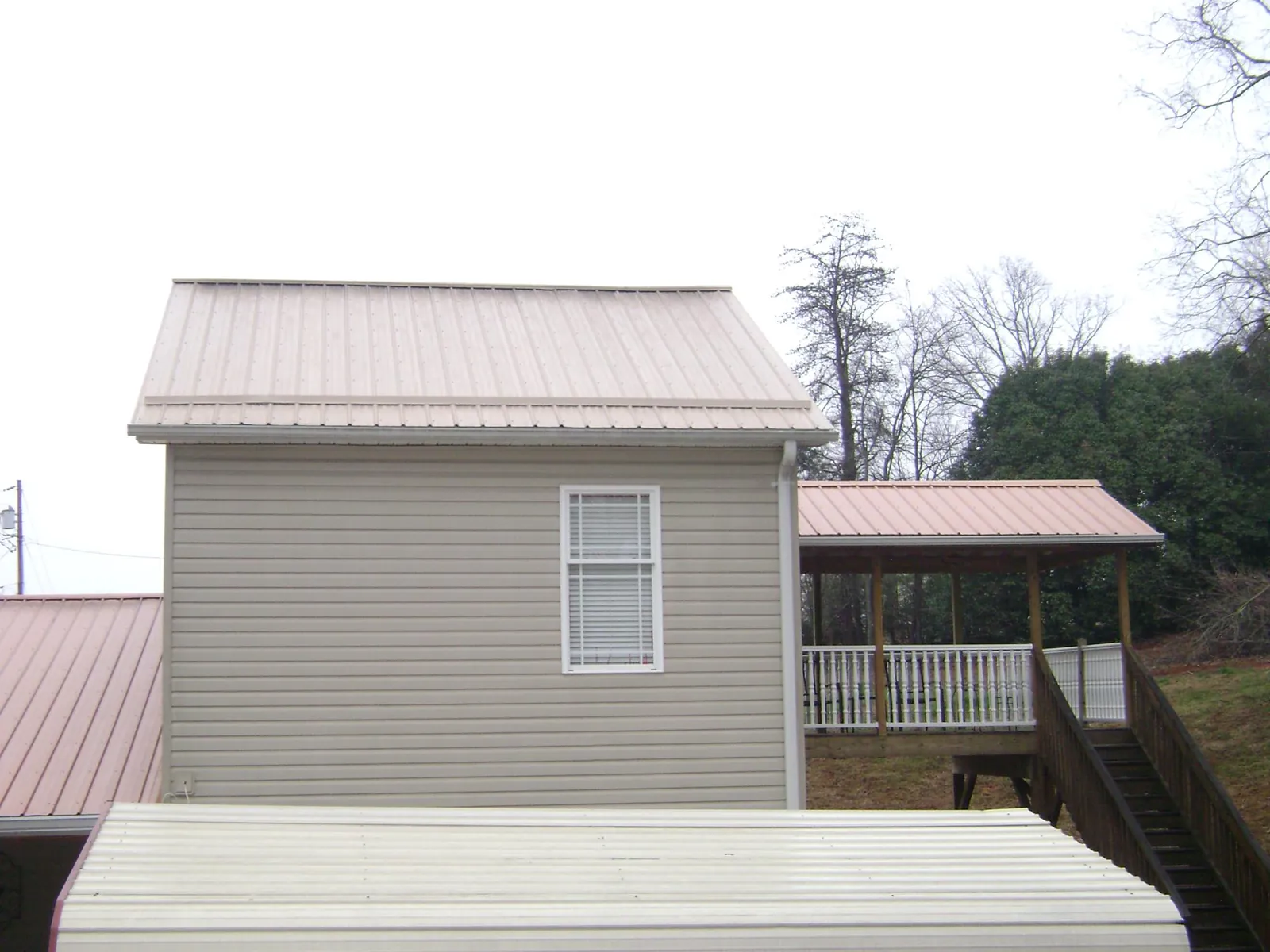 Tan metal roofs on a two story addition and attached porch, from a Roof Replacement job in Chickamauga