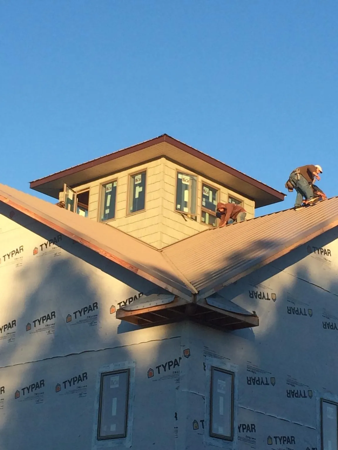 Roofers working around a rooftop cupola on a new metal roof at sunset — Roof Waterproofing in Chickamauga by Roofing Brothers
